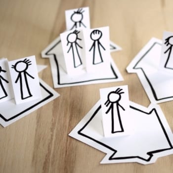 Display of paper houses and people placed on a wood floor.