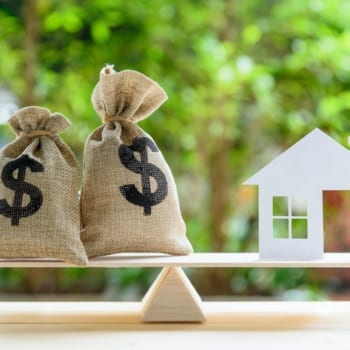 Weigh scale with 2 money bags and a mock-house