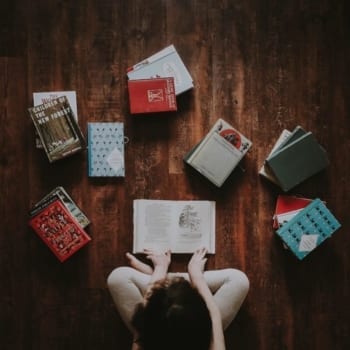 Child sitting on the floor reading books.