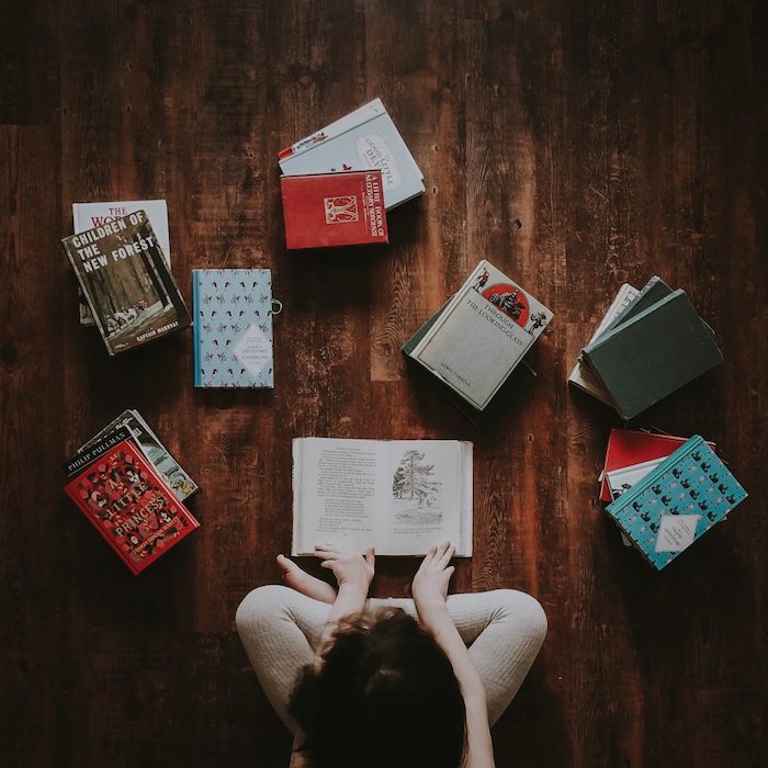 Child sitting on the floor reading books.
