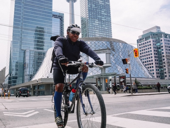 Man biking near the Roy Thomson Hall, Simcoe Street, Toronto, Toronto, ON, Canada with CN Tower in the background.