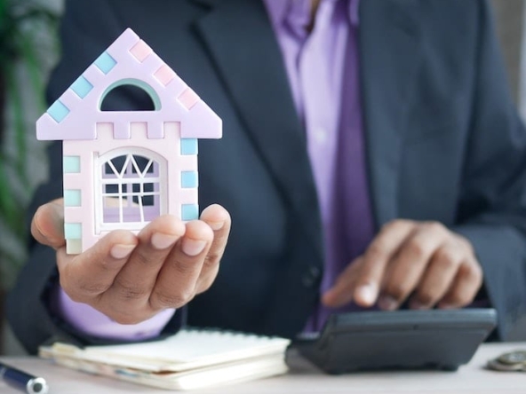 Person holding a small house indicating property purchase
